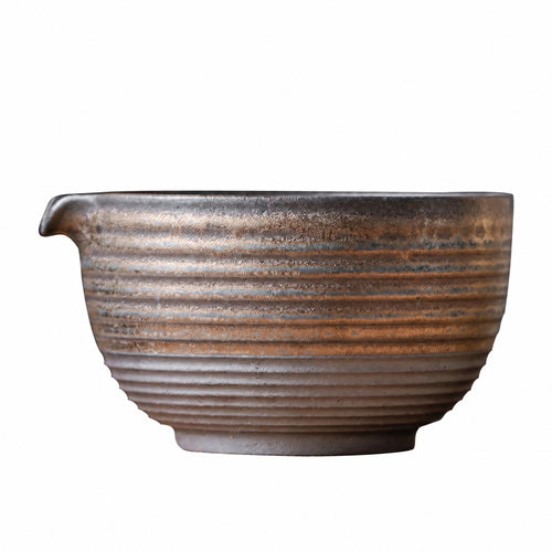 Ribbed kiln-glazed ceramic matcha bowl with a pouring spout in bronze and cream tones on a white background