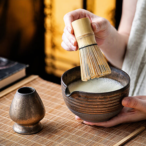 Four-piece matcha set in use: kiln-glaze bowl, bamboo whisk, whisk stand and scoop