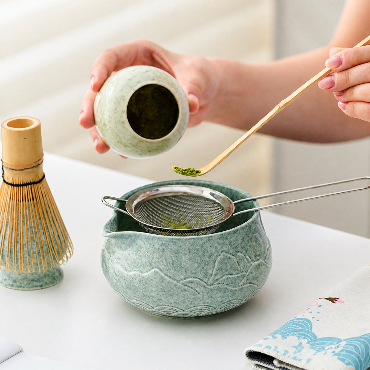 Sifting matcha powder through a fine mesh strainer for a ceramic matcha bowl